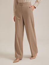 A lady wears khaki wide leg pants.